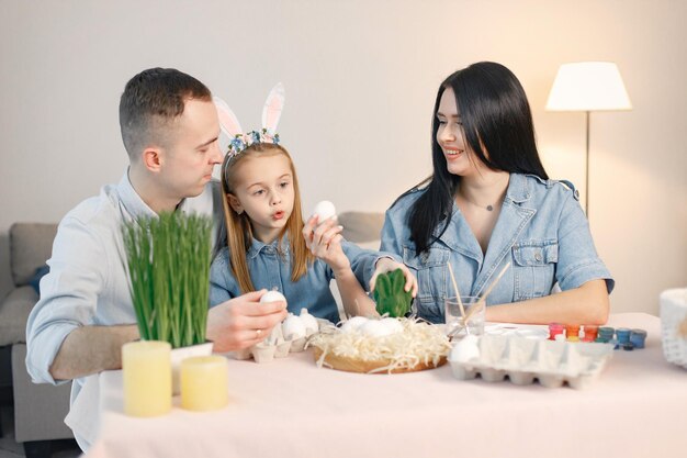 Gioiosa riunione di famiglia a tavola in una moderna cucina leggera e dipingendo insieme le uova di Pasqua