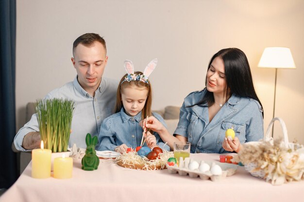 Gioiosa riunione di famiglia a tavola in una moderna cucina leggera e dipingendo insieme le uova di Pasqua