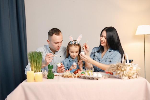 Gioiosa riunione di famiglia a tavola in una moderna cucina leggera e dipingendo insieme le uova di Pasqua