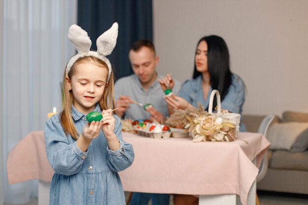 Gioiosa riunione di famiglia a tavola in una moderna cucina leggera e dipingendo insieme le uova di Pasqua