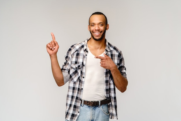 Gioioso amichevole afro-americano giovane iwearing camicia casual che indica dal dito