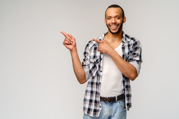 Gioioso amichevole afro-americano giovane iwearing camicia casual che indica dal dito