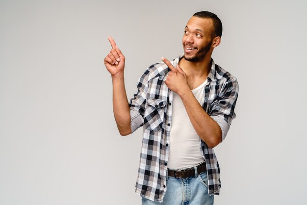 Gioioso amichevole afro-americano giovane iwearing camicia casual che indica dal dito