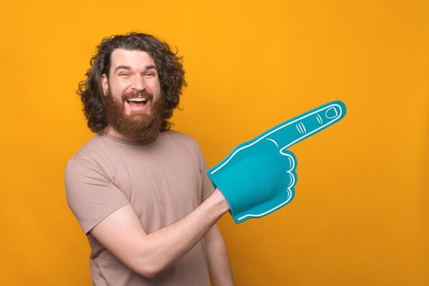 gioioso bell'uomo barbuto sorridente e indicando con il guanto del ventilatore