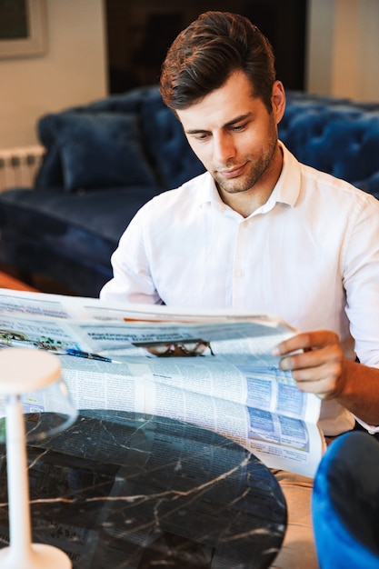 Giornale di lettura pensieroso giovane uomo vestito formale