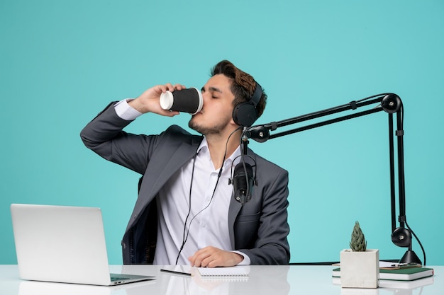 Giornalista blogger giovane ragazzo carino e bello in abito grigio che registra video bevendo caffè