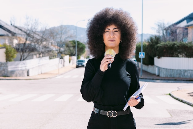 Giornalista giornalista televisiva donna con i capelli afro che racconta una notizia per strada