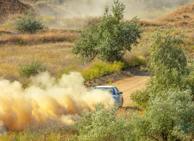 Giornata di sole estivo. Pista sterrata per il rally. Un'auto attraversa una curva e fa molta polvere 05