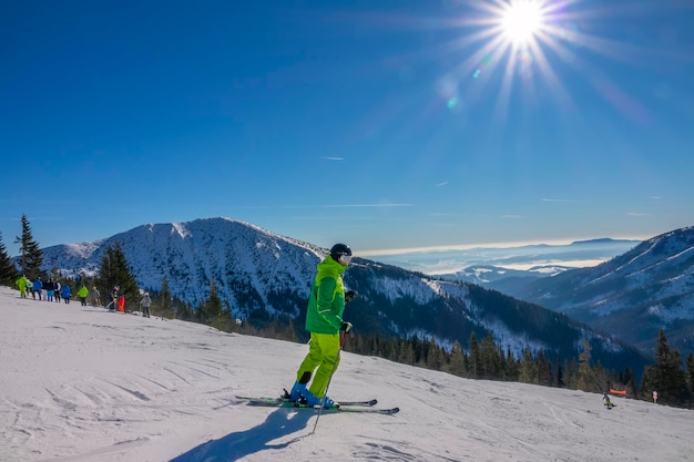 Giornata di sole invernale. Sciatore irriconoscibile in giacca gialla percorre un'ampia pista da sci