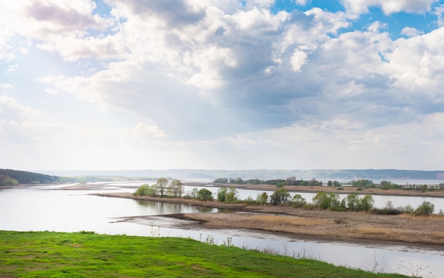 Giornata di sole primaverile sul prato vicino al paesaggio rurale panoramico del fiume