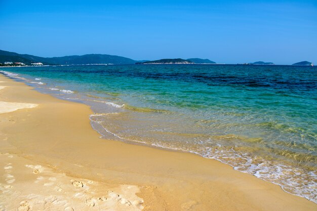 Giornata di sole, scricchiolii di sabbia, mare turchese limpido, barriere coralline sulla costa della baia di Yalong nel Mar Cinese Meridionale. Sanya, isola di Hainan, Cina. Paesaggio della natura.