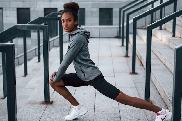 Giornata di stretching La giovane donna afroamericana in abiti sportivi si allena all'aperto