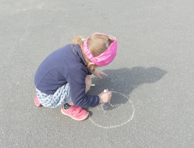 Giornata estiva su asfalto con gesso disegna una bambina.