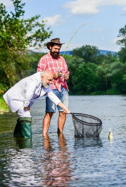 Giornata in famiglia papà in pensione e figlio barbuto maturo Due amici maschi che pescano insieme pesce volante hobby di uomo d'affari pensione pesca pescatori felici Buon profitto Cattura e concetto di pesca