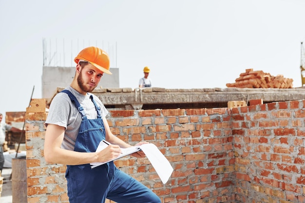 Giornata intensa Il giovane operaio edile in uniforme è impegnato nell'edificio incompiuto