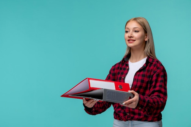 Giornata internazionale degli studenti bella ragazza bionda in camicia rossa a quadri sorridente e in possesso di cartelle di file