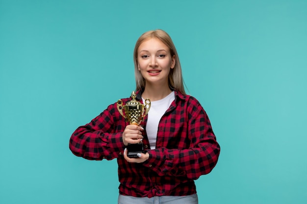 Giornata internazionale degli studenti ragazza carina in camicia rossa a quadri con in mano un trofeo d'oro