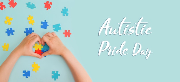 Giornata mondiale della consapevolezza dell'autismo Le mani di un bambino piccolo che tiene puzzle colorati su sfondo blu