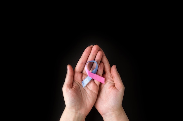 Giornata mondiale della tiroide Mani di adulti che tengono un nastro per la consapevolezza del cancro alla tiroide in blu rosa teal