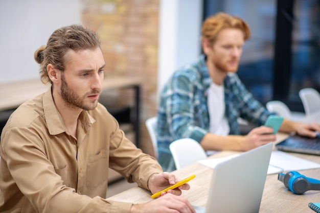 Giornata piena. Due ragazzi che sembrano seri mentre lavorano sui laptop