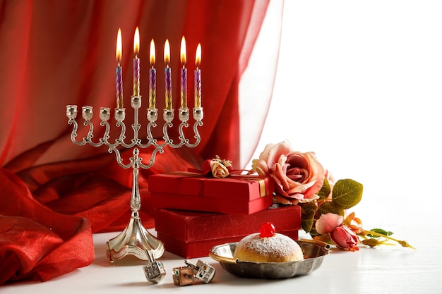 Giorno 5 della festa religiosa ebraica Hanukkah con festa Hanukkah (candelabro tradizionale), giocattoli trottola (dreidels), scatole regalo, ciambella e Tanakh