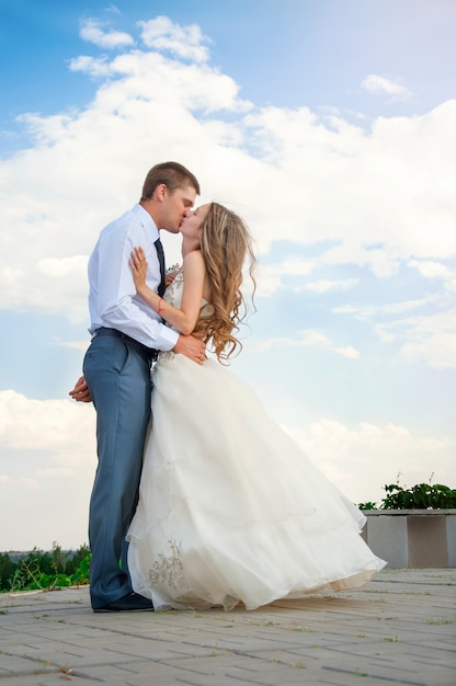 Giorno del matrimonio. Bella sposa tra le braccia dello sposo su Sky