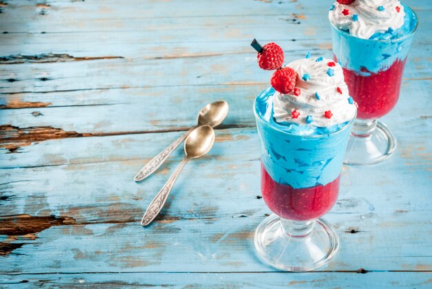 Giorno dell'Indipendenza. 4 luglio. Dessert a strati di gelato, mousse di lamponi e bacche montate, decorato in stile patriottico americano. Su un vecchio tavolo di legno blu. Copia spazio