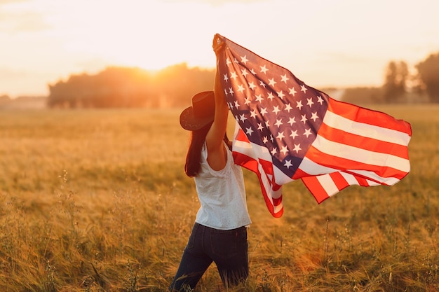 Giorno dell'indipendenza patriottica 4 luglio Contadina nel campo agricolo con bandiera americana al tramonto