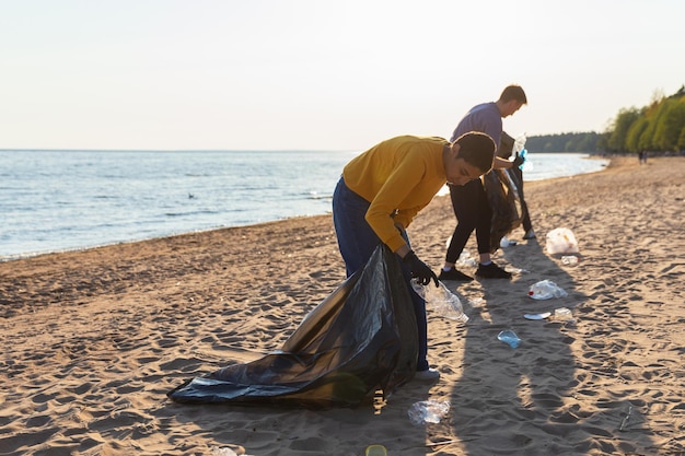 Giorno della Terra volontari attivisti raccoglie spazzatura pulizia della spiaggia zona costiera donna e uomini mette
