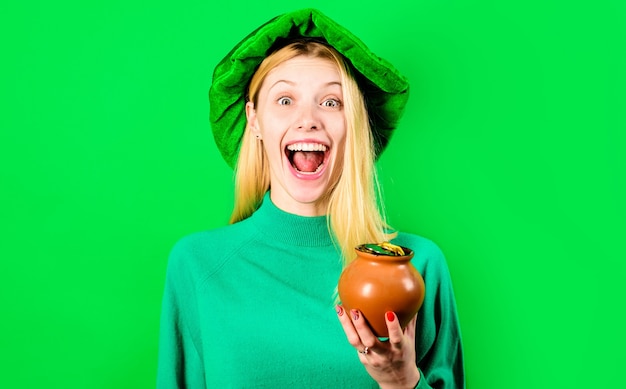 Giorno di San Patrizio. La donna felice in cappello del leprechaun tiene il vaso con oro. Tradizioni irlandesi. San Patrizio.