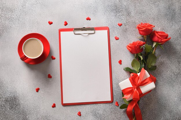 Giorno di San Valentino vuoto per lettera d'amore con caffè rose rosse regalo romantico su sfondo grigio vista dall'alto biglietto di auguri e spazio di copia