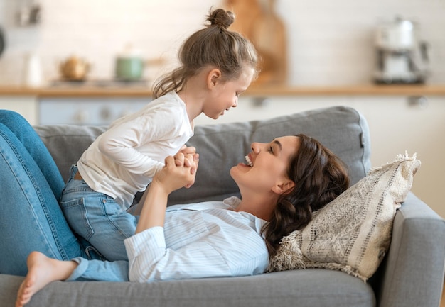 Giorno felice! La mamma e sua figlia bambina stanno giocando, sorridendo e abbracciando. Vacanza in famiglia e stare insieme.