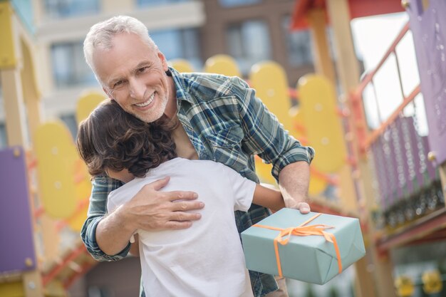 Giorno felice. Padre felice che dà un regalo a suo figlio ed entrambi sembrano eccitati