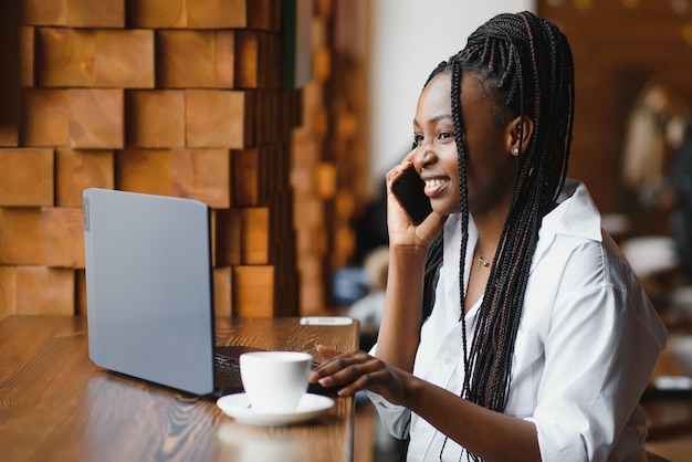 Giorno fortunato Donna nera emotiva che guarda il laptop che stringe i pugni e urla mentre lavora allo spazio della copia del caffè