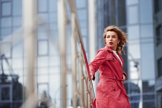 Giorno ventoso. Una bella donna adulta con un caldo cappotto rosso passeggia in città durante i fine settimana