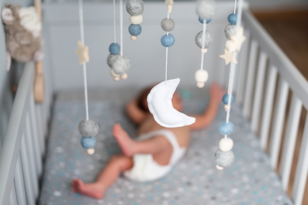 Giostrina per culla con stelle, pianeti e luna appesa sopra il neonato che dorme. Giocattoli fatti a mano per bambini sopra la culla del neonato. I primi giocattoli ecologici per bambini in feltro e legno