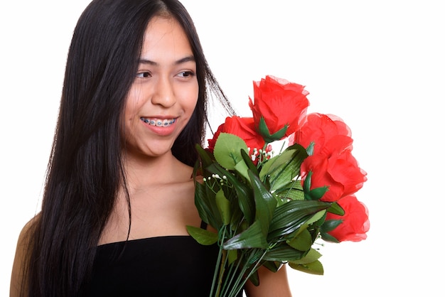 Giovane adolescente asiatico felice sorridente mentre si tiene un mazzo di rose