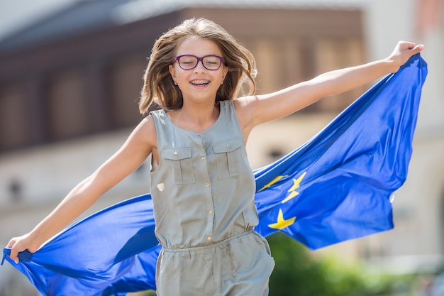 Giovane adolescente che sventola con la bandiera dell'Unione europea in città