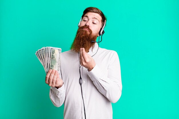 Giovane adulto capelli rossi barbuto cool agente uomo con auricolare e banconote in dollari