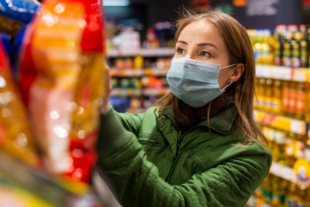 Giovane adulto che indossa una maschera di protezione e l'acquisto di prodotti