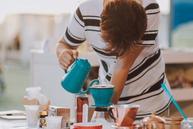 Giovane adulto che produce caffè in una tazza all'aperto