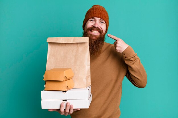 Giovane adulto con i capelli rossi barbuto uomo fresco con un sacchetto di carta con cibo da asporto