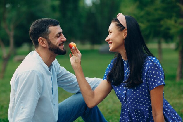 Giovane adulto donna e uomo coppia picnic al prato di erba verde nel parco.