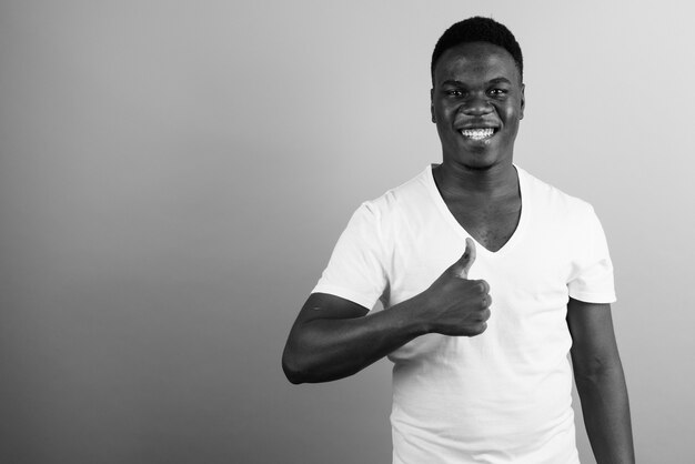 giovane africano che indossa una camicia bianca contro il muro bianco. bianco e nero