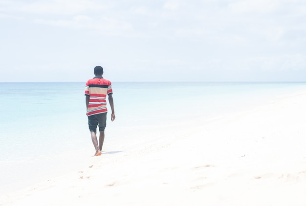 Giovane africano nero che cammina sulla spiaggia