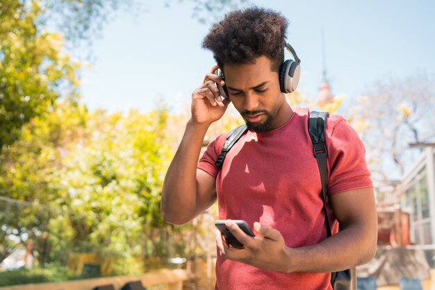 Giovane afro che ascolta la musica con il suo telefono cellulare