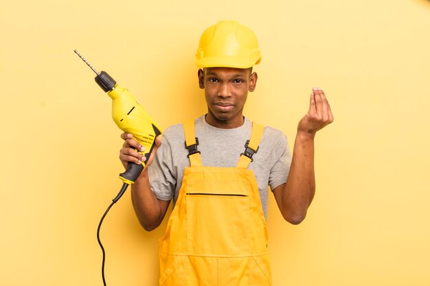 Giovane afro nero che fa un gesto di capice o denaro dicendoti di pagare il lavoratore domestico con un trapano