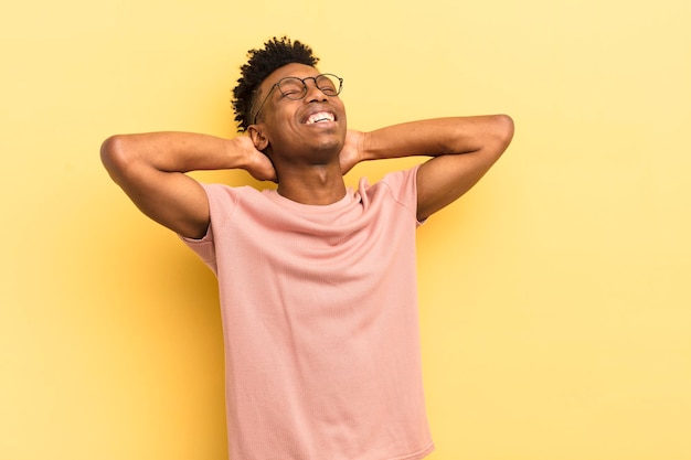 Giovane afro nero che sorride e si sente rilassato, soddisfatto e spensierato, ridendo positivamente e agghiacciante