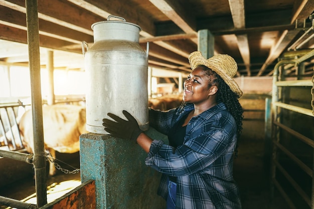 Giovane agricoltore africano donna che tiene il bidone del latte all'interno della stalla Focus sul viso