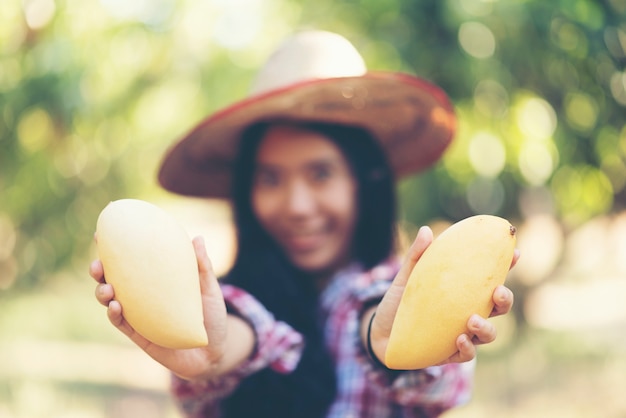 Giovane agricoltore asiatico che seleziona la frutta del mango in azienda agricola organica